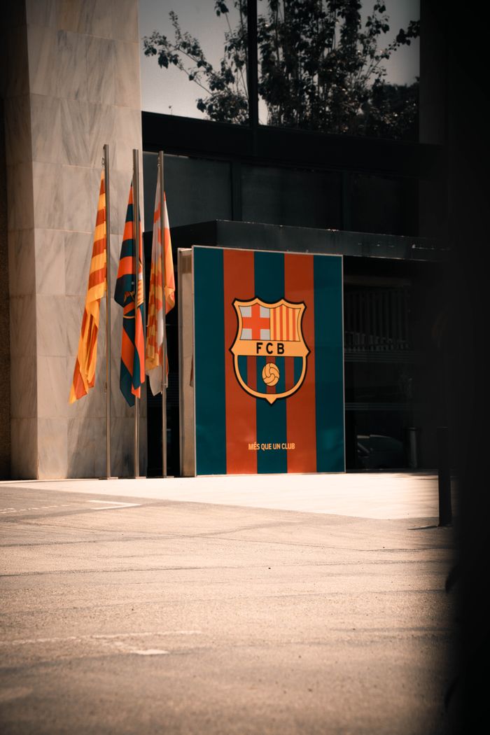 Barcelona FC entrance with team flags and emblem in a vibrant urban setting.